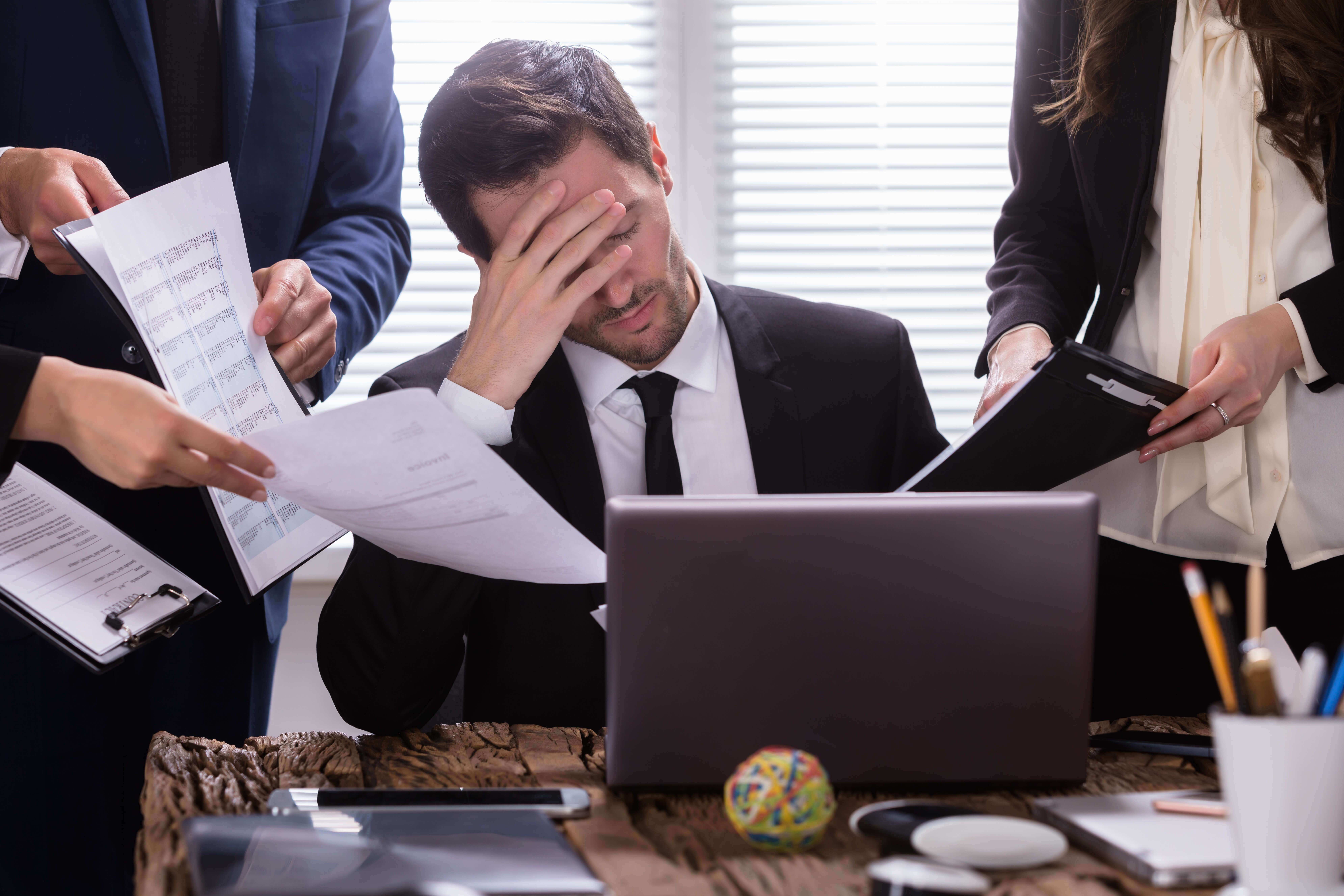 Stressed person surround by people with paperwork