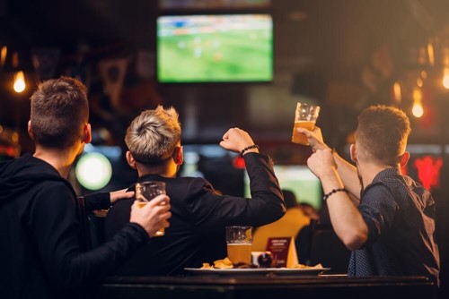 football supporters watch game on TV in bar