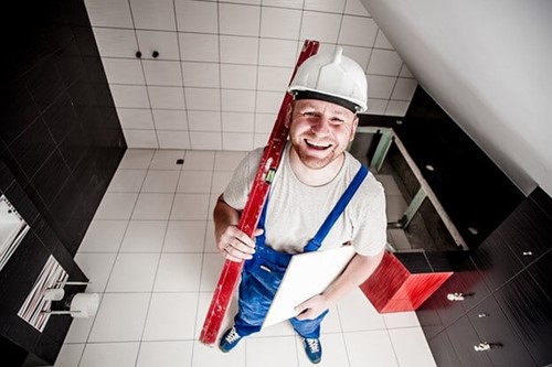 A workman holding his tools and smiling at the camera