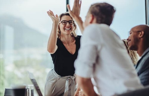 Two people celebrating improved productivity thanks to metal health and wellbeing counselling.