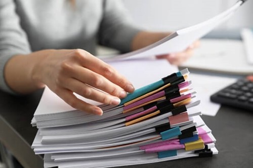 an employee looking for method statements and risk assessments outlining the control measures in a stack of paper