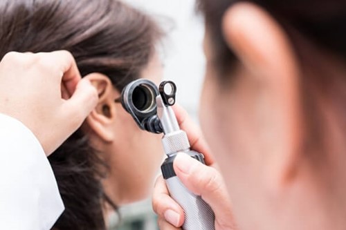 Employee exposed to work noise being examined by ear doctor due to having difficulty hearing normal conversation.