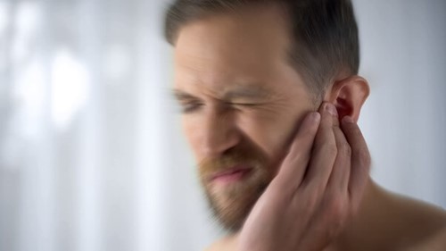 Employee holding hear having been exposed to high levels of noise and noisy power tools without hearing checks.