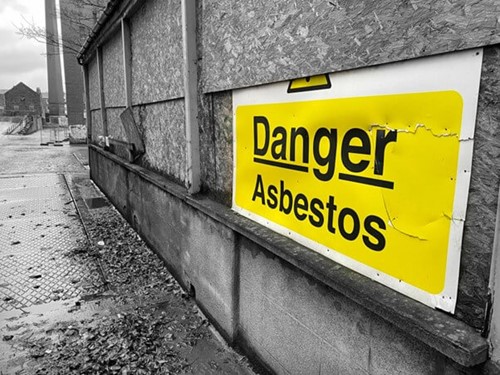 A warning sign denoting asbestos in the workplace, indicating the risk of asbestos exposure leading to the chance of asbestos related disease.