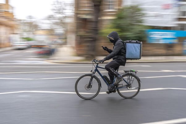 A person riding a bike with a food delivery box on their back