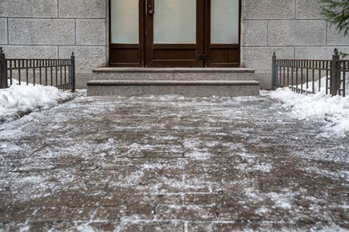 An icy path leading to an office door representing a slip hazard for employees.