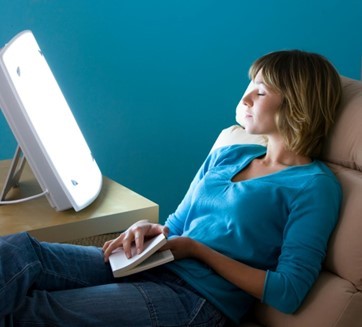 woman using a SAD lamp to counter the effects of seasonal affective disorder.