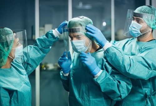 Employees being helped put on PPE in a medical setting