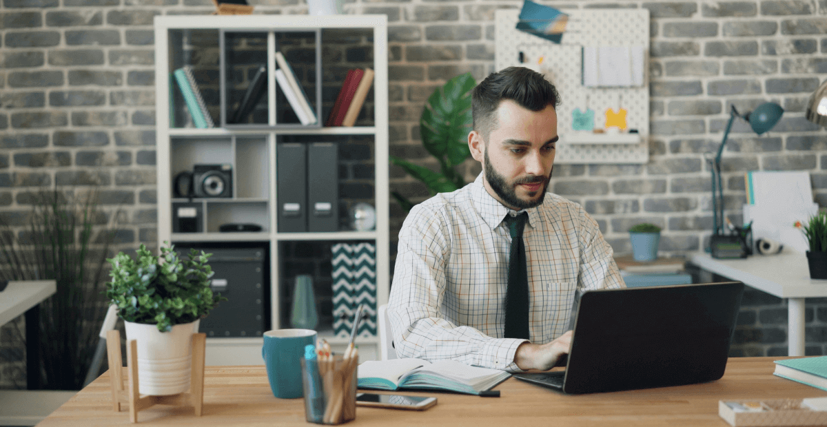 a man working at desk in office on computer laptop