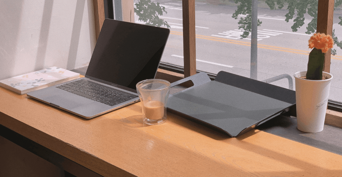 laptop computer on desk next to printer and cup of coffee