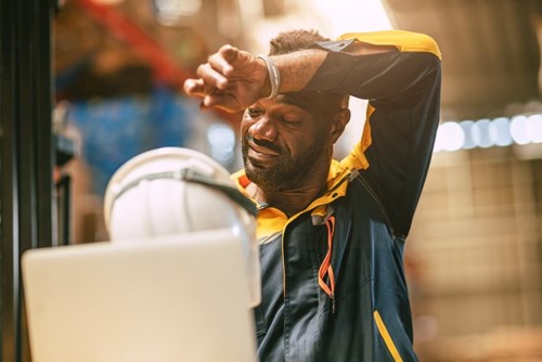 An employee with his hand on his forehead suffering from occupational fatigue.