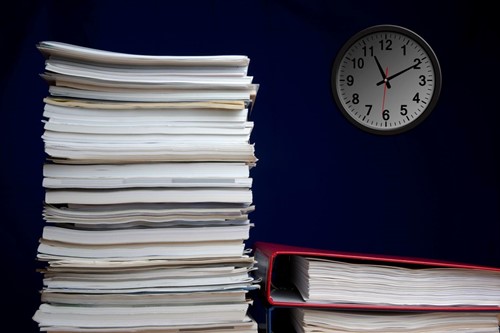 A desk stacked with paperwork indicating working out of hours resulting in time off in lieu.